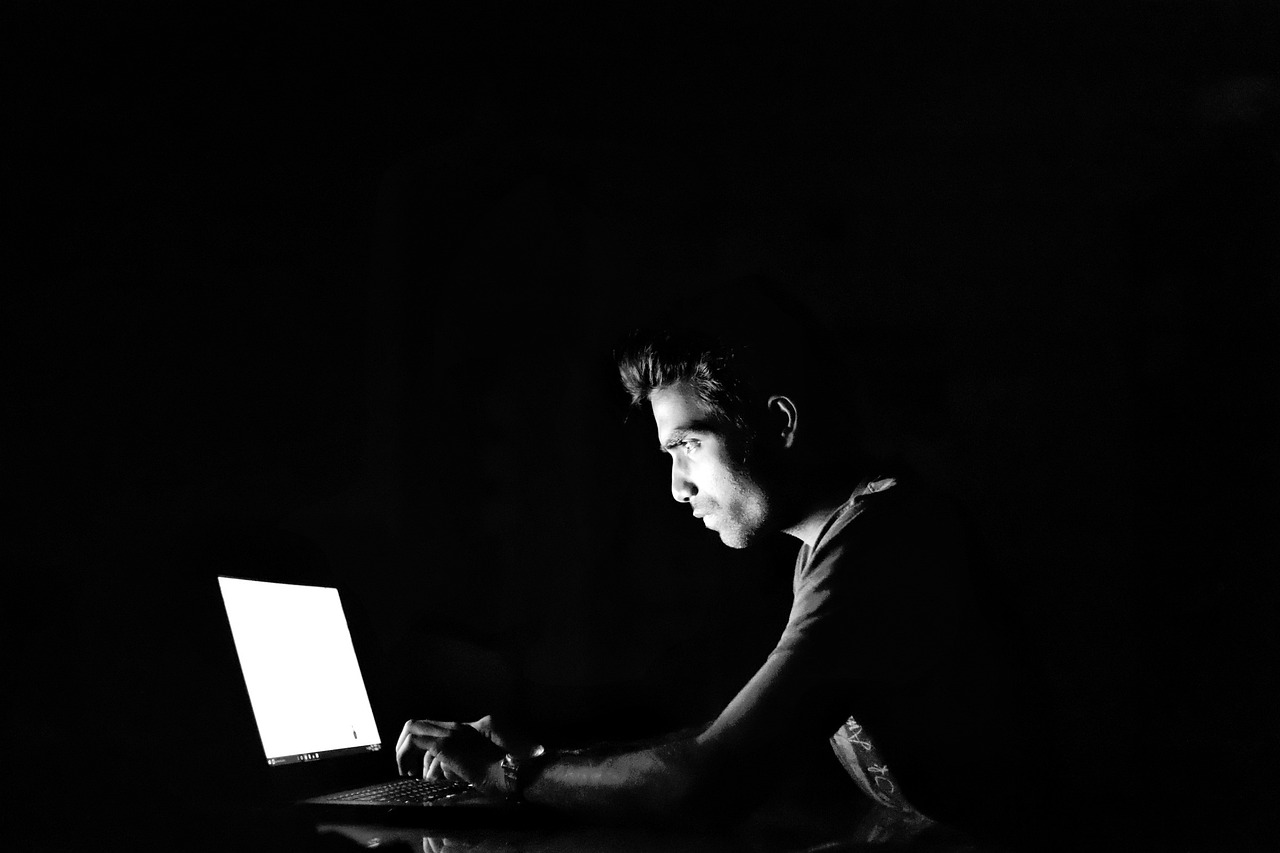 a man sitting in front of a laptop computer, a black and white photo, by Max Dauthendey, pexels, computer art, backlit glow, portrait of dangerous, calm night. over shoulder shot, stock photo