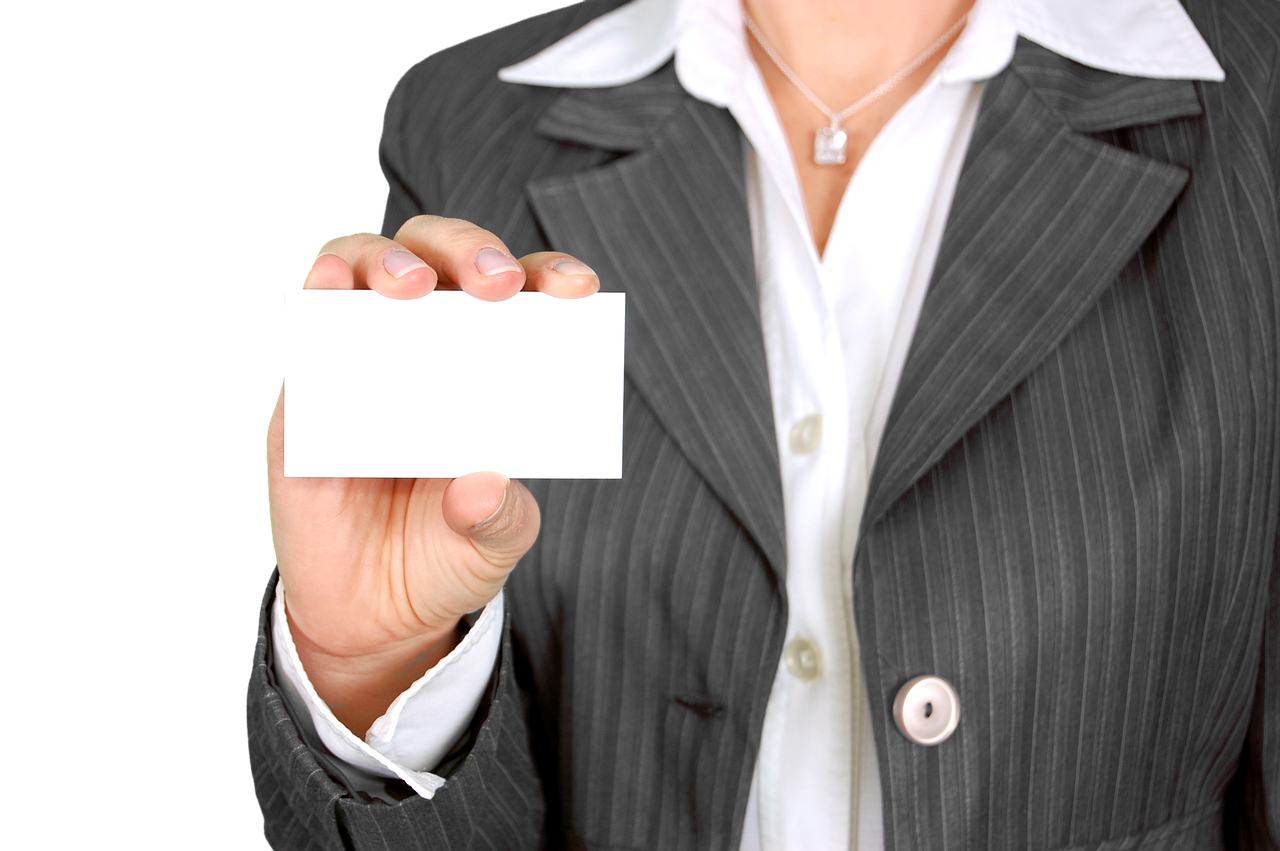 a woman in a business suit holding a business card, a photo, by Edward Corbett, compressed jpeg, edited, white, wikipedia