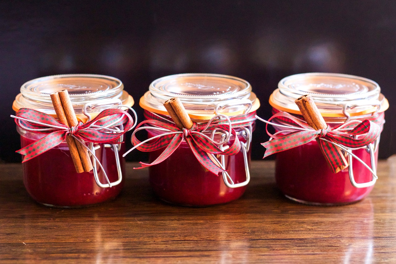 three jars of jam sitting on top of a wooden table, inspired by Slava Raškaj, pexels, crimson themed, ribbon, avatar image, festive