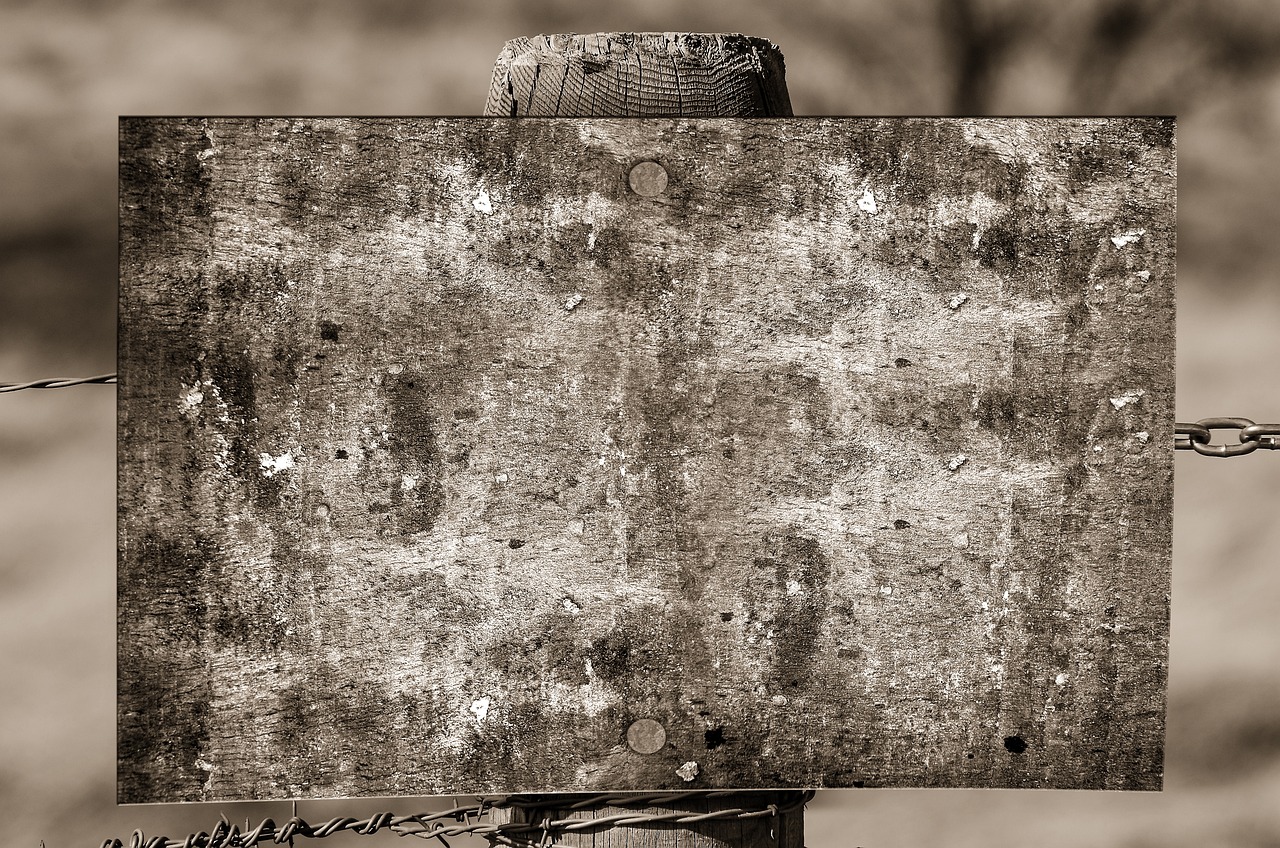 a black and white photo of a rusty sign, inspired by Dorothea Lange, high resolution texture, rough wooden fence, scratched photo