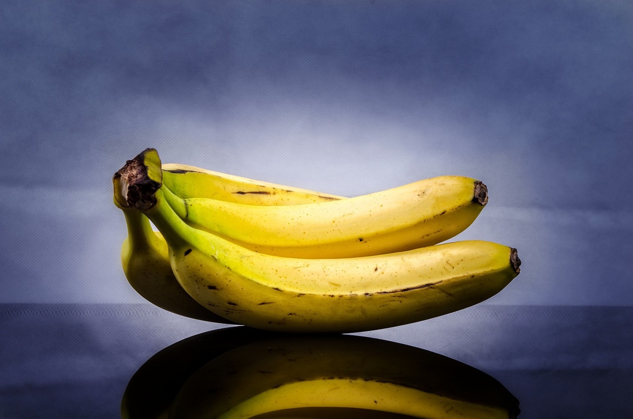 a bunch of bananas sitting on top of a table, by Matt Stewart, pexels, hyperrealism, with a blue background, mirrored, profile shot, stock photo