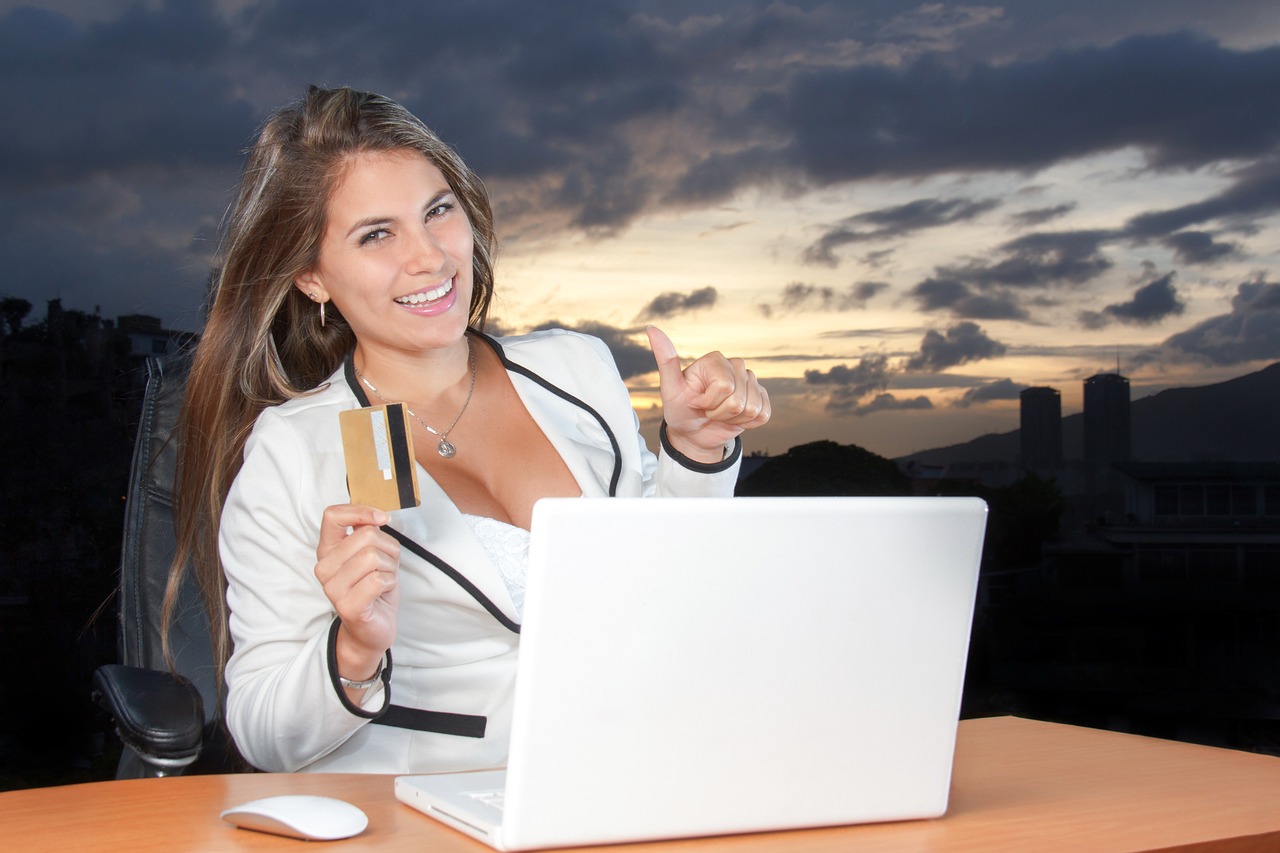 a woman holding a credit card and a laptop, a stock photo, shutterstock, sunset!, funny professional photo, doing a thumb up, elegant look