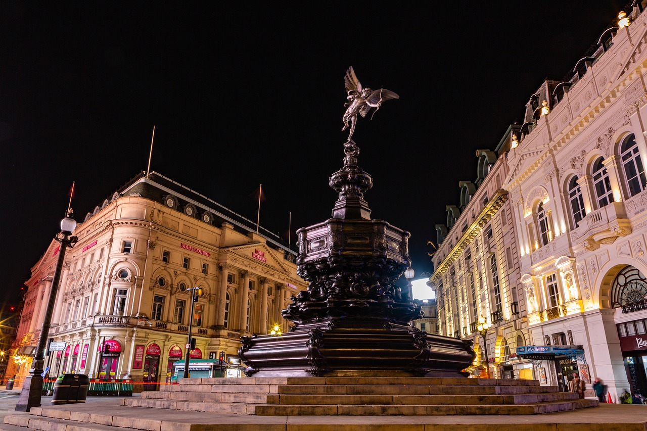 a statue in the middle of a city at night, a statue, by Joseph Severn, shutterstock, victorian england style, broadway, shot with a canon 20mm lens, eros