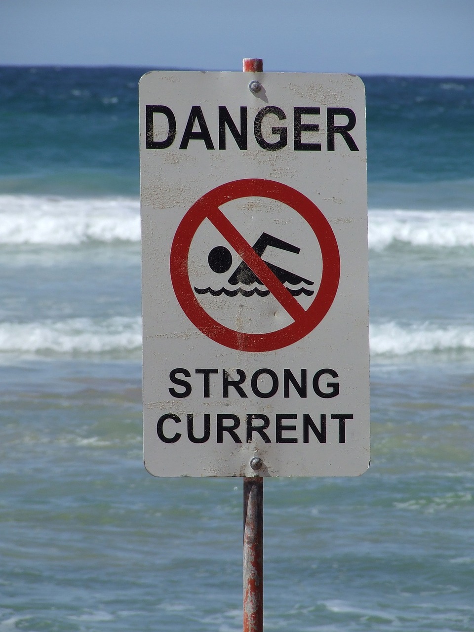 a sign warning people not to swim in the ocean, by David Garner, strong rim light, menacing!, strong man, currents