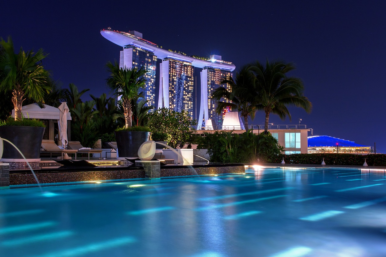 a swimming pool at night with a hotel in the background, by Joseph Severn, shutterstock, singapore, roof garden, paradise, led