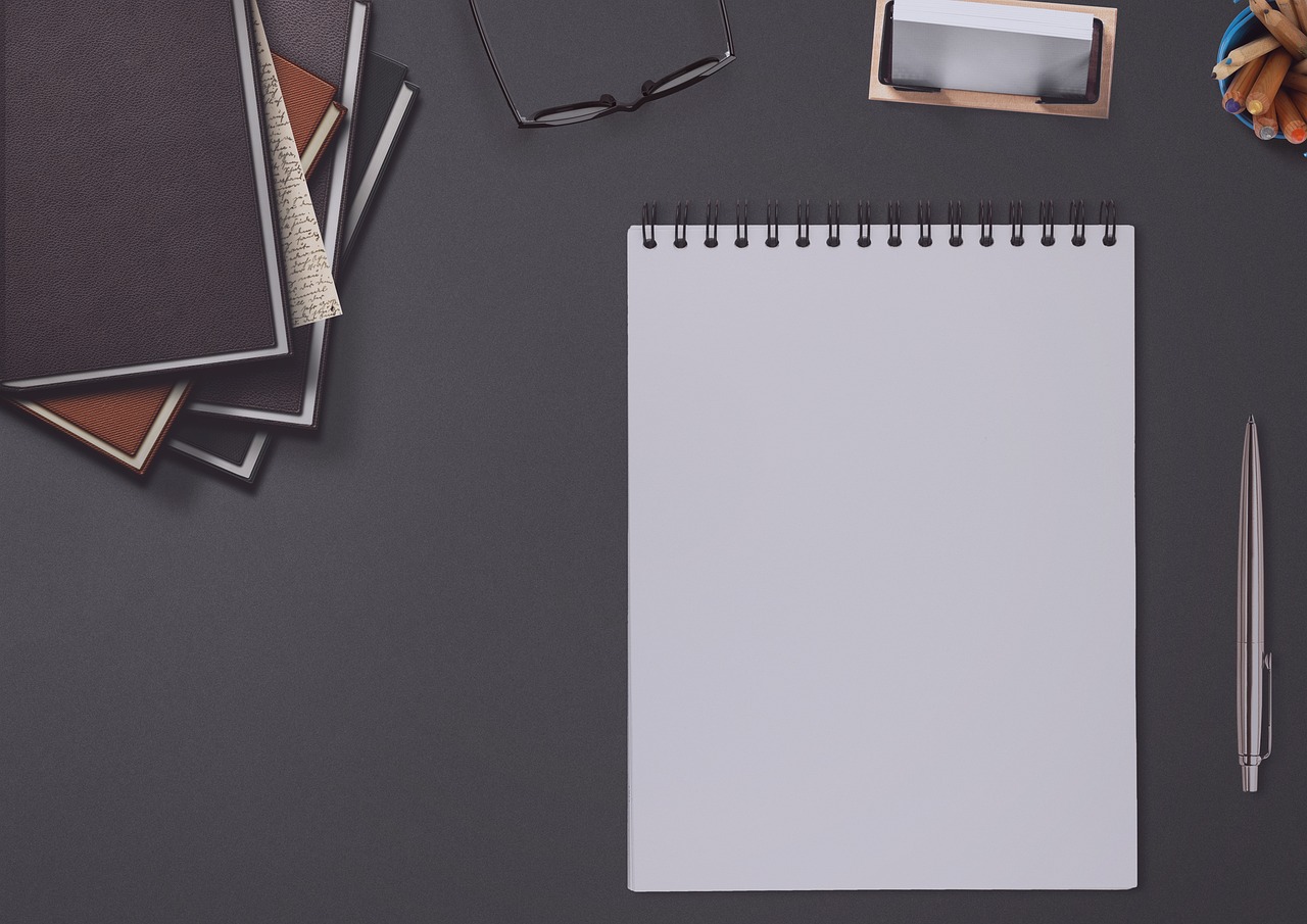 a notepad sitting on top of a desk next to a cup of coffee, by Andrei Kolkoutine, unsplash, visual art, on a flat color black background, banner, realistic footage, on a gray background
