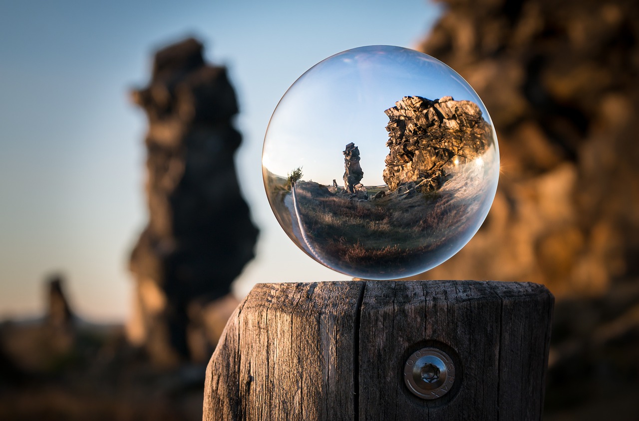 a glass ball sitting on top of a wooden post, a picture, by Vladimír Vašíček, sci-fi of iceland landscape, refractive crystal, tight shot of subject, rocky foreground
