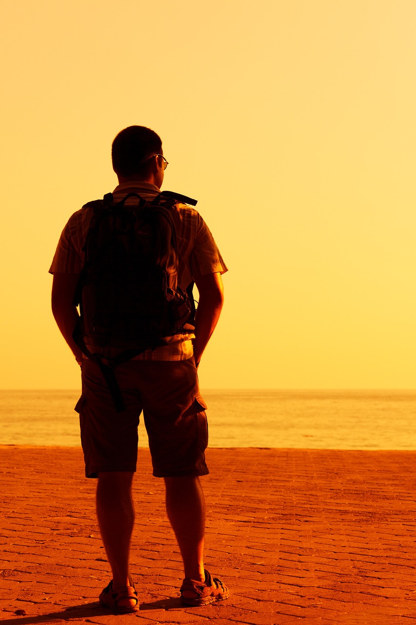 a man standing on top of a sandy beach, shutterstock, a man wearing a backpack, backlight photo sample, in front of an orange background, stock photo