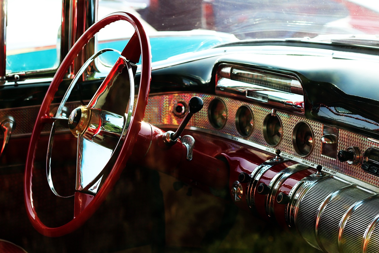 a close up of a steering wheel and dashboard of a car, a portrait, by Tom Carapic, pexels, retrofuturism, turquoise and venetian red, chrome reflections, fantastic vendor interior, rustic