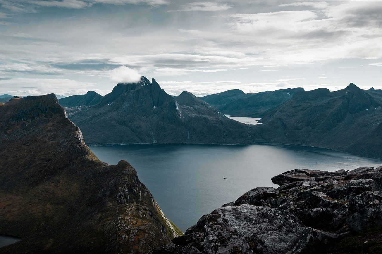 a person standing on top of a mountain next to a body of water, by Johannes Voss, hero shot, jörmungandr, wide shot photo