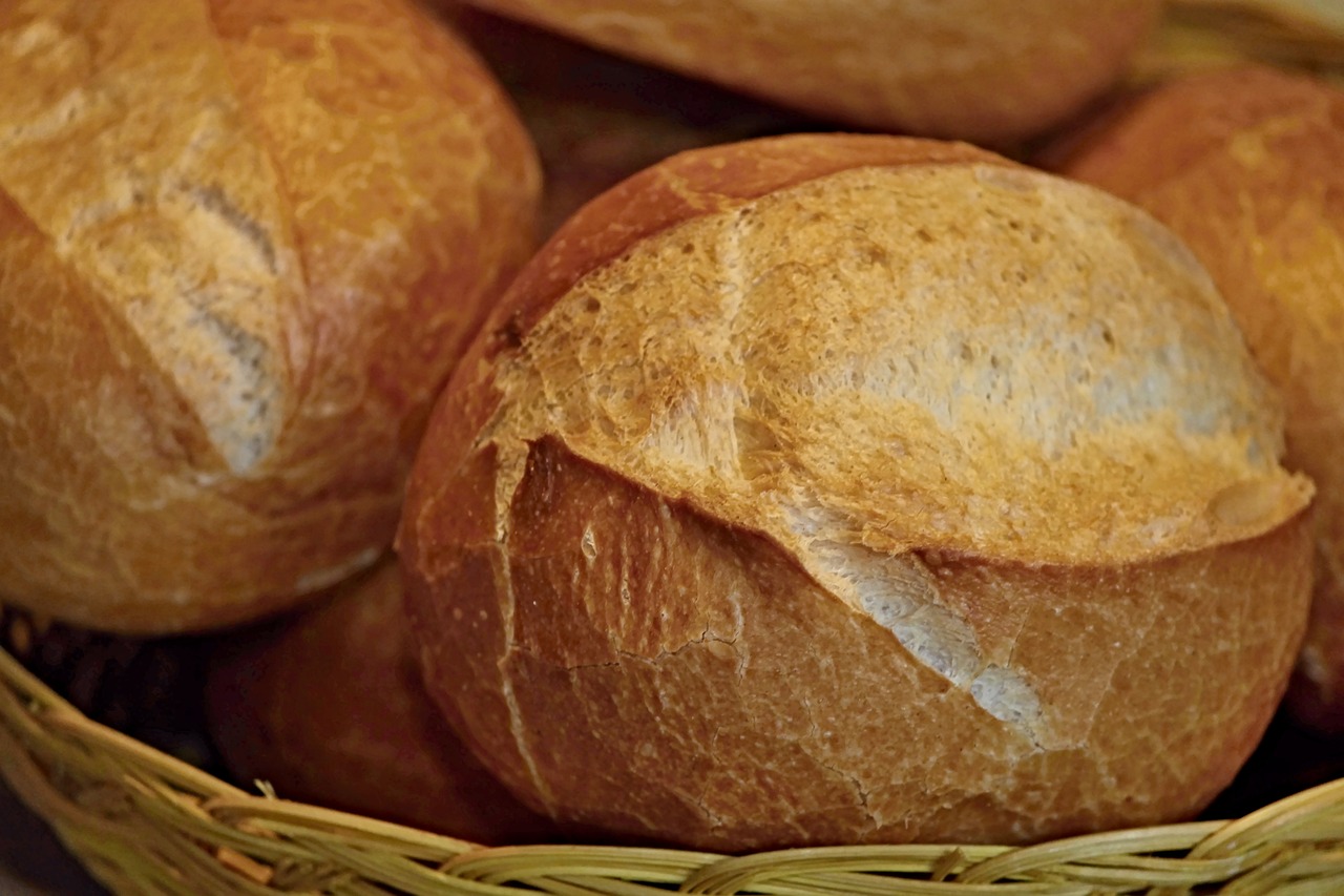 a basket filled with lots of bread sitting on top of a table, pexels, bauhaus, dynamic closeup, video still, mineral grains, round-cropped