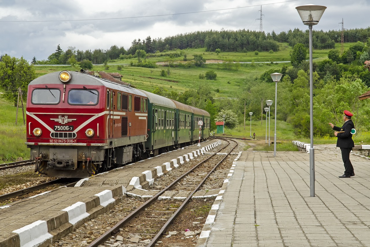 a red train traveling down train tracks next to a lush green hillside, dau-al-set, southern slav features, terminal, dsrl photo