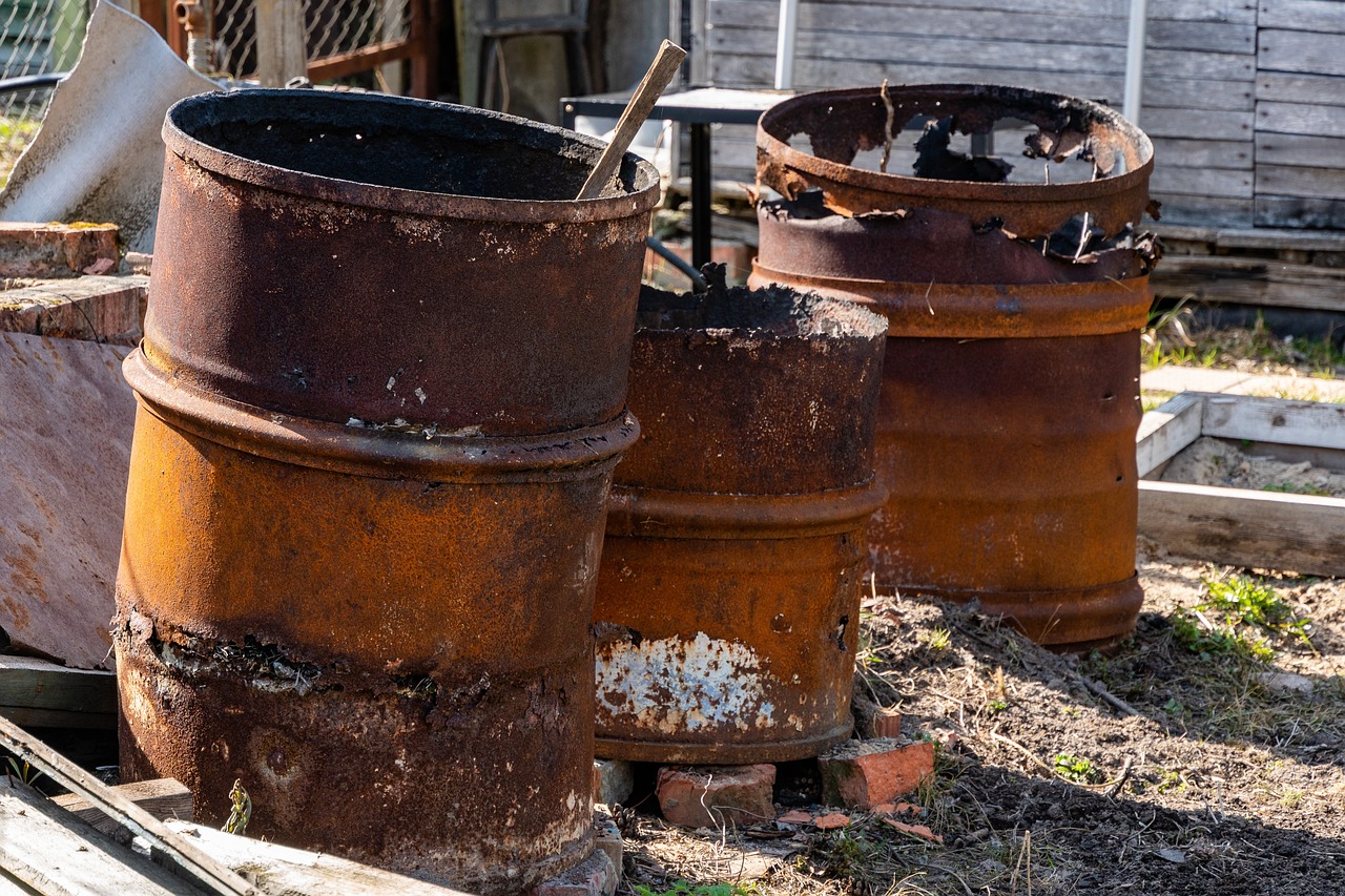 a couple of rusty barrels sitting next to each other, by Arnie Swekel, auto-destructive art, pots and pans, lots of embers, australian, in the yard