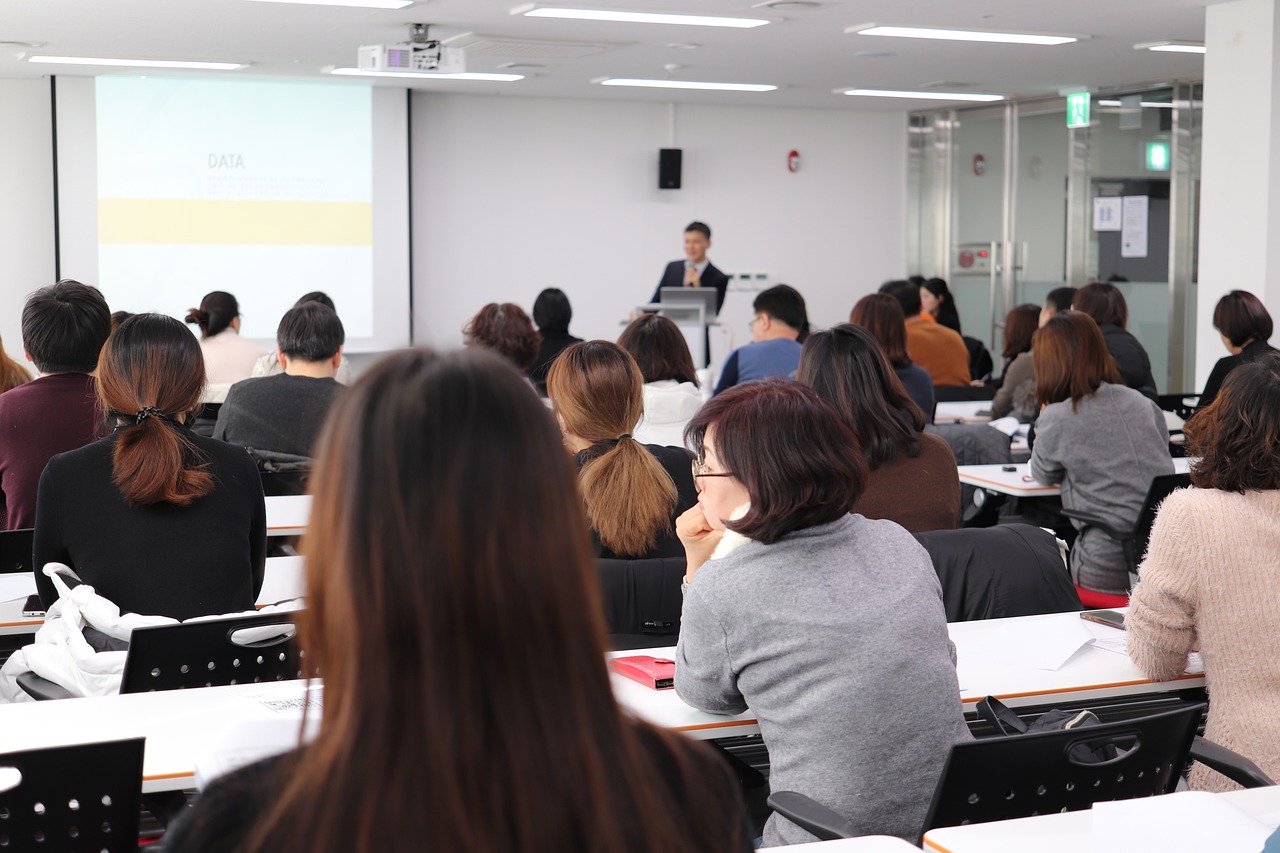 a group of people sitting at desks in front of a projector screen, a picture, by Jang Seung-eop, flickr, unrea 5, academia, maternal, product introduction photo