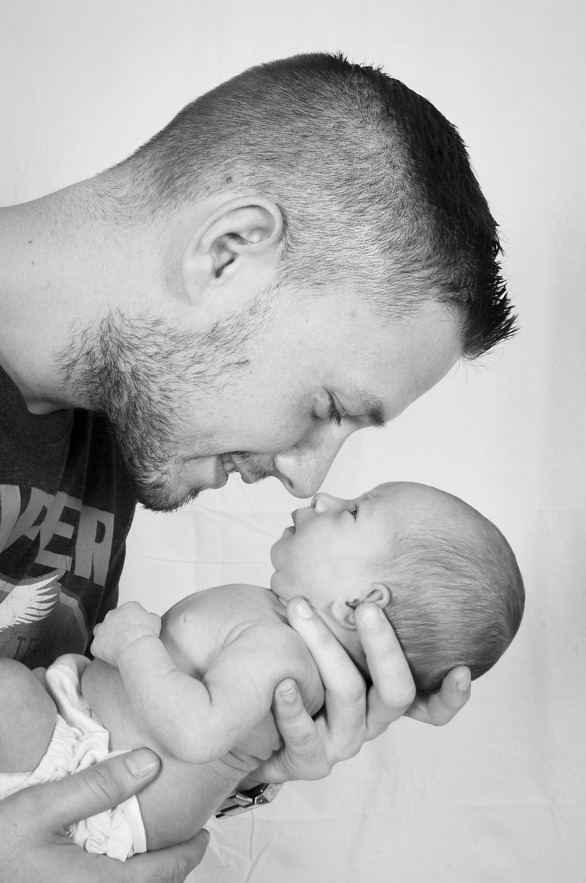 a black and white photo of a man kissing a baby, pixabay contest winner, ultra realistic, looking to his side, color photo, portait photo profile picture