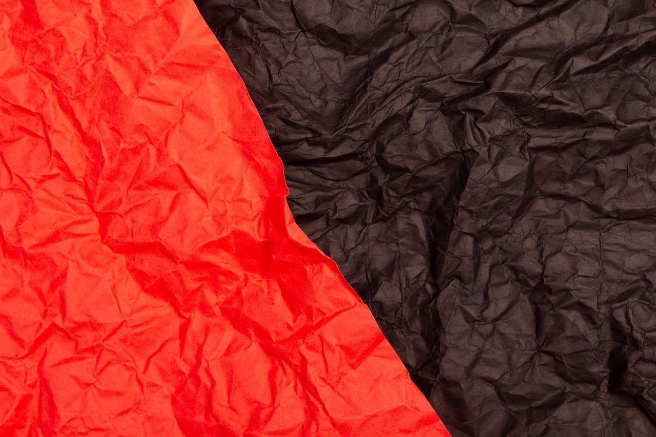 a close up of a red and black piece of paper, a stock photo, minimalism, tight wrinkled cloath, two colors, mountaineous background, close-up product photo