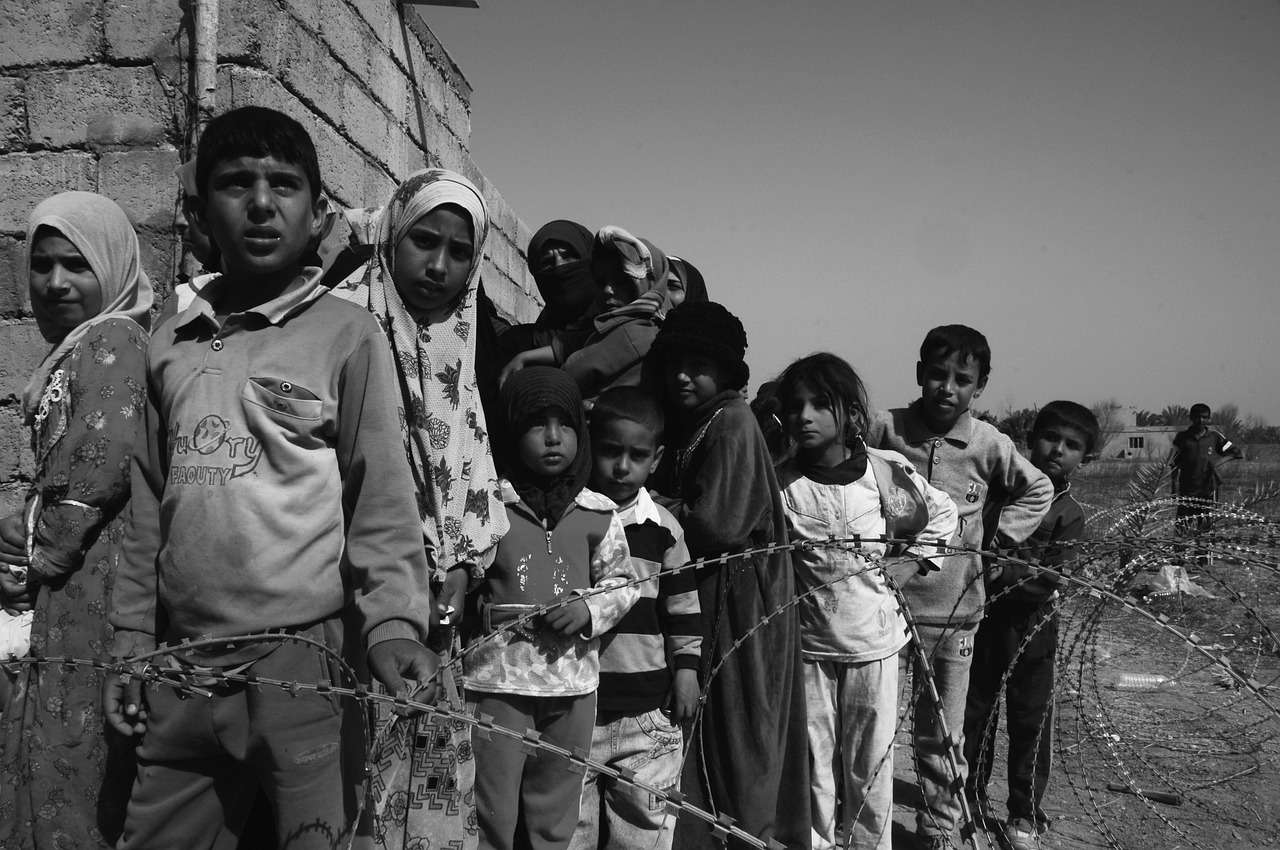 a group of people standing next to a barbed wire fence, a black and white photo, by Ibrahim Kodra, flickr, hurufiyya, children, jordan, kris kuksi, center of image