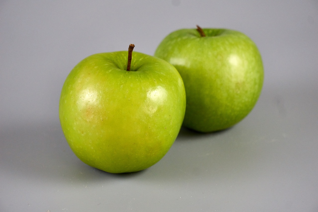 two green apples sitting next to each other on a table, extremely lifelike, 3 4 5 3 1, male and female, john baer