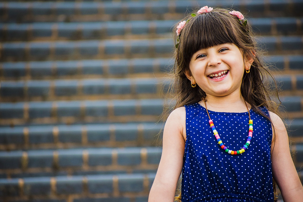 a little girl in a blue dress smiles at the camera, a picture, pexels, colorful adornments, 4 5 mm bokeh, confident smile, motivational