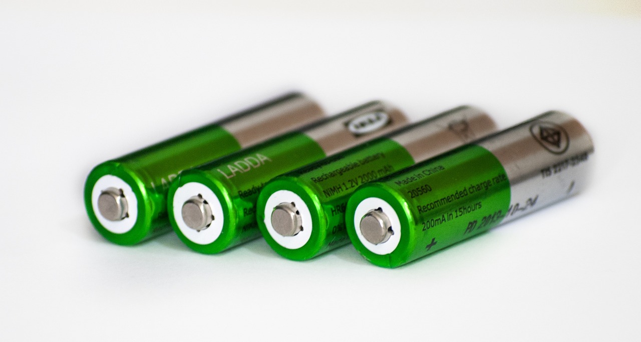 four green batteries sitting side by side on a white surface, a picture, inspired by Luigi Kasimir, pixabay, neo-dada, silver dechroic details, fluorescent light, 3 mm, circular