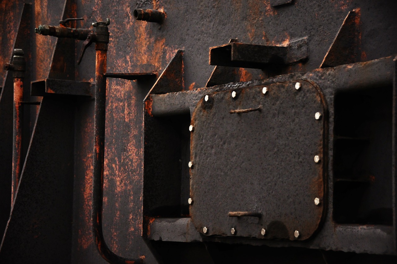 a close up of a metal structure with rivets, by Richard Carline, flickr, assemblage, black and brown colors, an abandoned rusted train, dark grey and orange colours, abstract photography