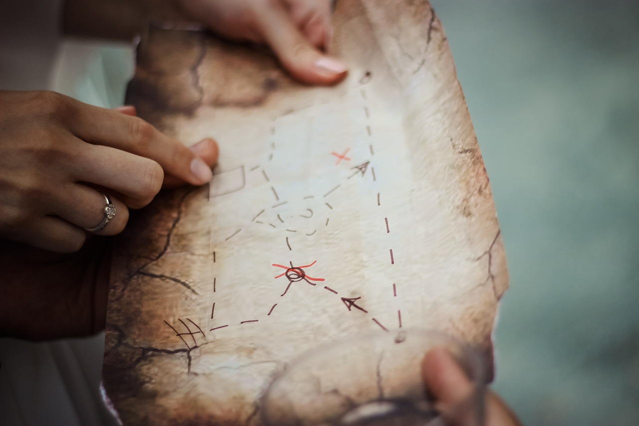 a person holding a piece of paper with writing on it, by Emma Andijewska, pexels, conceptual art, pirates treasure map, stock photo, zelda breath of the wild map, close-up from above