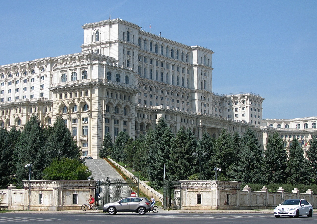 a large white building sitting on the side of a road, inspired by György Rózsahegyi, sitting at the parlament meeting, elaborate latticed balconies, wikimedia commons, mu pan