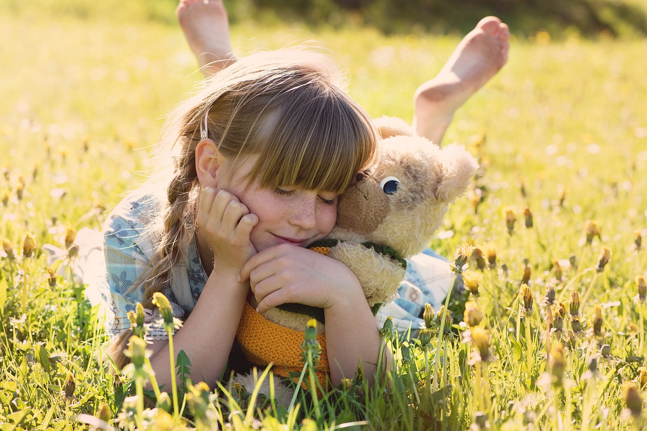 a little girl laying in the grass with a teddy bear, a picture, inspired by Elsa Beskow, istockphoto, holding a rabbit, toy photo, hugging each other
