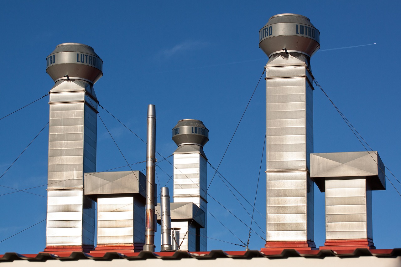 a couple of chimneys sitting on top of a roof, shutterstock, modernism, stainless steel, three towers, heavy conduits, shiny silver