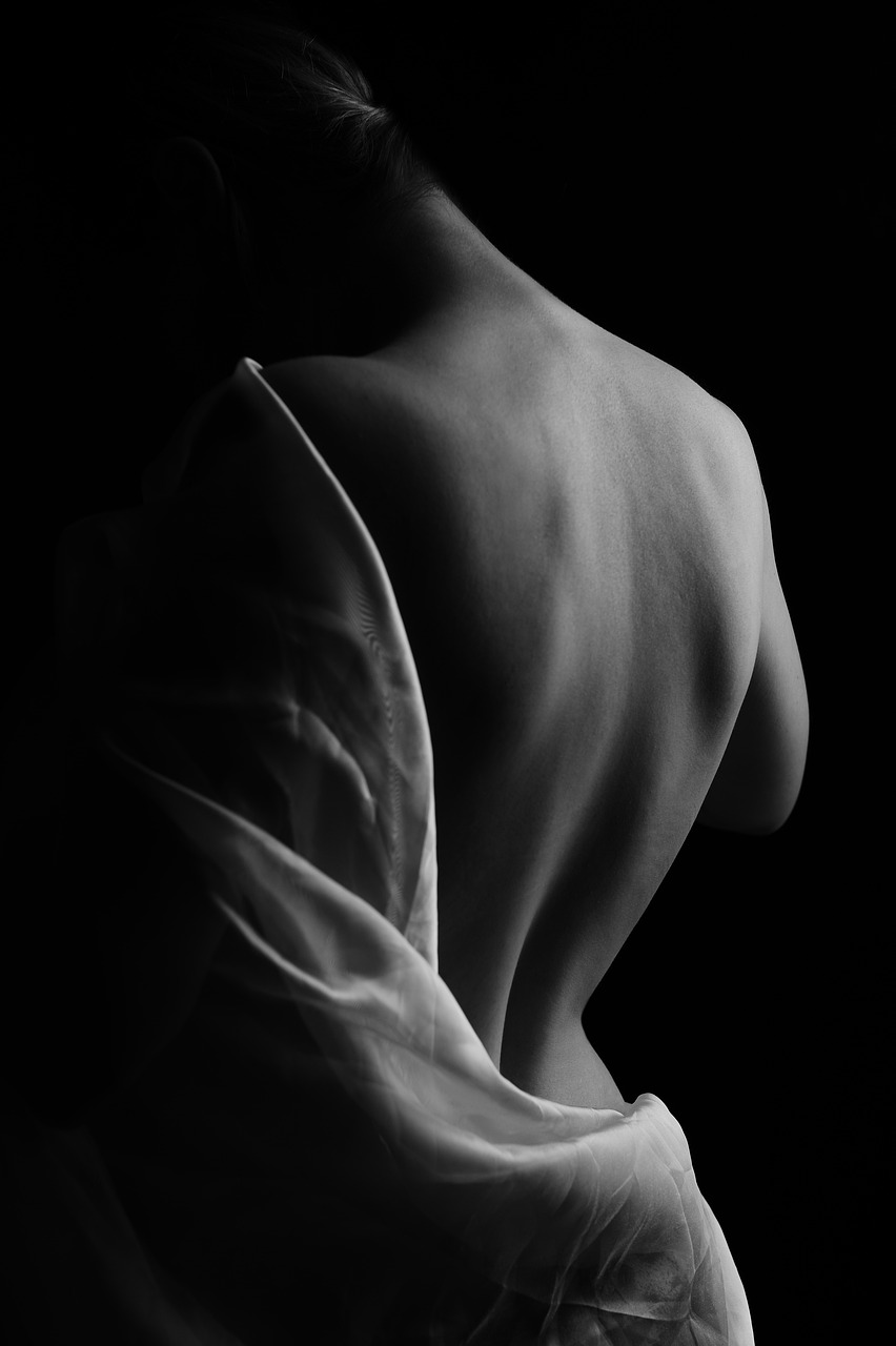 a black and white photo of a naked woman, inspired by Lillian Bassman, art photography, folds of fabric, in style of caravaggio, difraction from back light, lower back of a beautiful