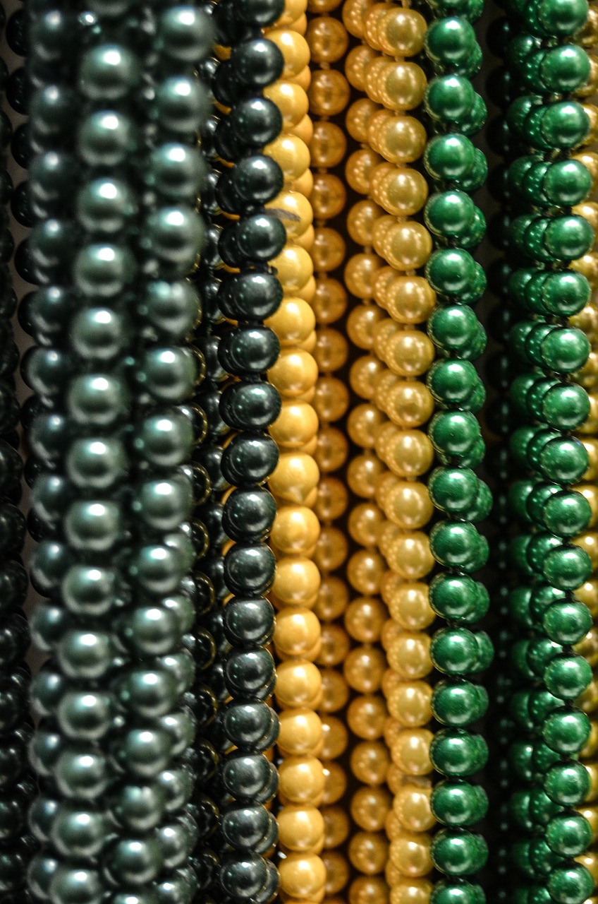 a close up of a bunch of beads, by Karel Štěch, pexels, renaissance, gradient black green gold, gold and pearl necklaces, in a row, hong kong