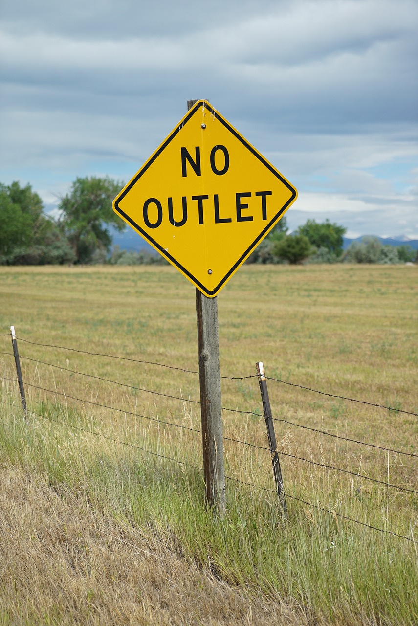a yellow no outlet sign sitting on the side of a road, a stock photo, by Robert Childress, shutterstock, pierced, field, sparsely populated, albuquerque