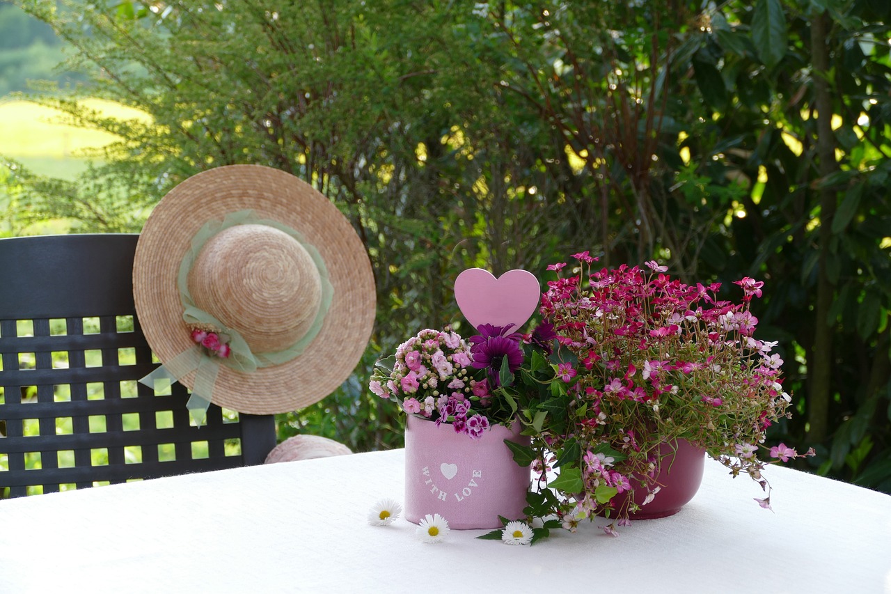 a hat sitting on top of a table next to a flower pot, romanticism, heart made of flowers, garden environment, with soft pink colors, family friendly