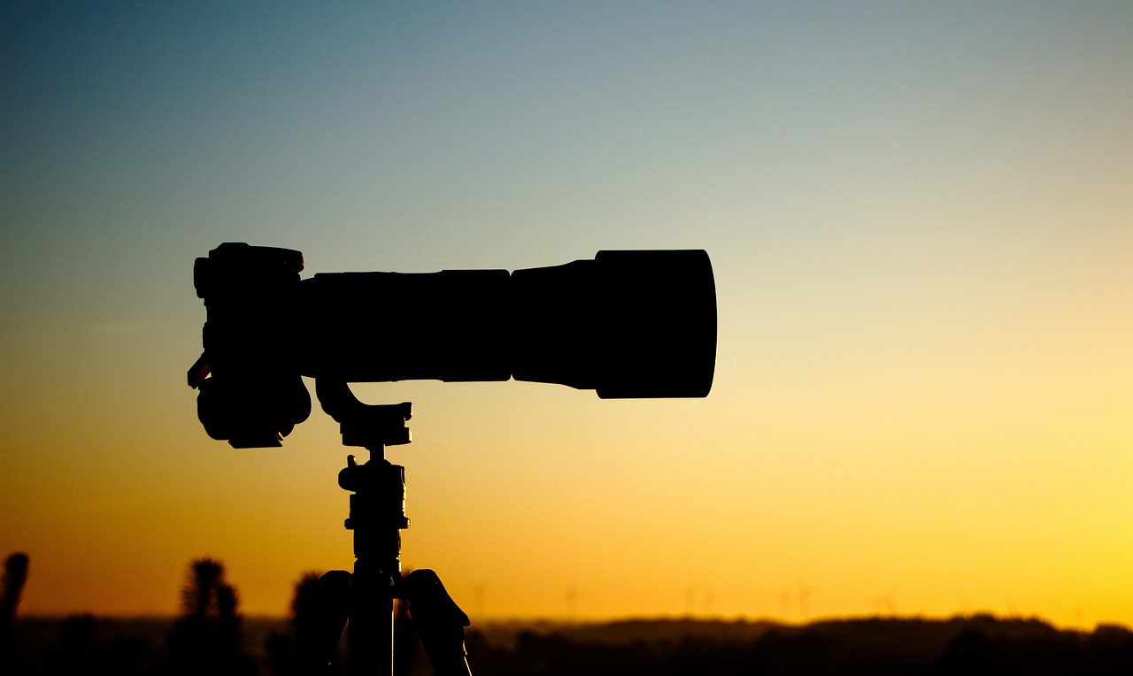 a close up of a camera on a tripod, a picture, by Thomas Häfner, shutterstock, silhouetted, super long shot, big monocular, sunset photo