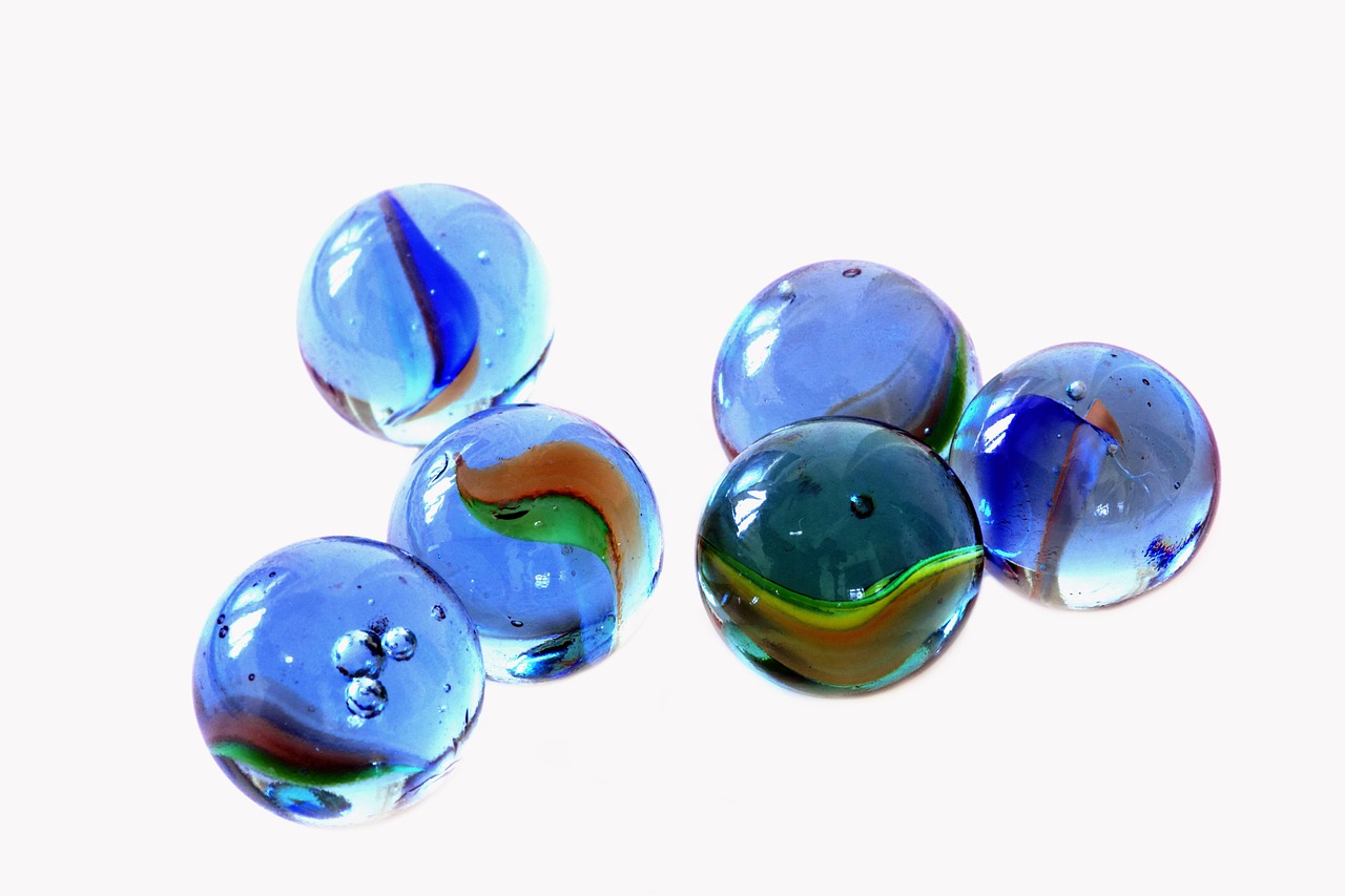 a group of glass marbles sitting on top of a table, an illustration of, by Karel Štěch, flickr, figuration libre, blue and green rainbow fire, detailed product photo, blue jewellery, blue and orange