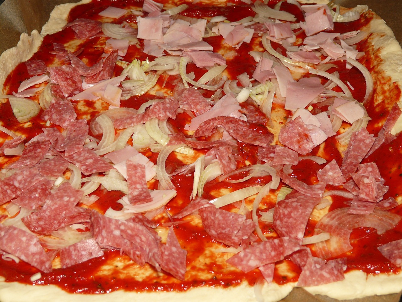 a pizza sitting on top of a pan covered in toppings, a photo, inspired by Vittore Carpaccio, pixabay, dada, covered with pink marzipan, extra onions and ketchup, salami, wip