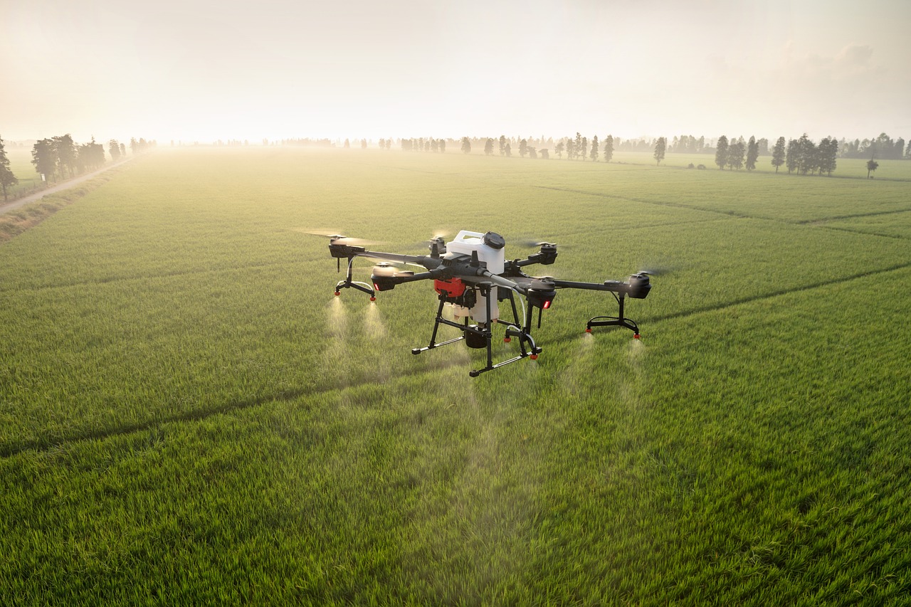 a large drone flying over a lush green field, a stock photo, by Jakob Gauermann, shutterstock, spraying liquid, high detailed photo, very detailed picture, morning glow