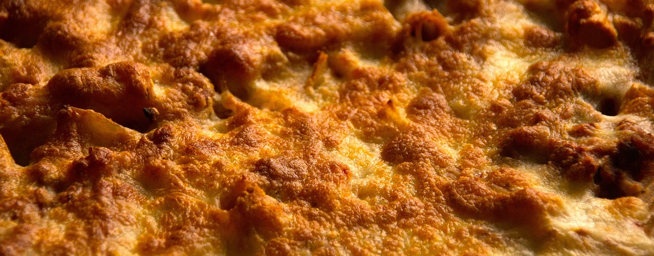 a pizza sitting on top of a pan covered in cheese, by Aleksander Gierymski, hdr detail, ruffles, grain”