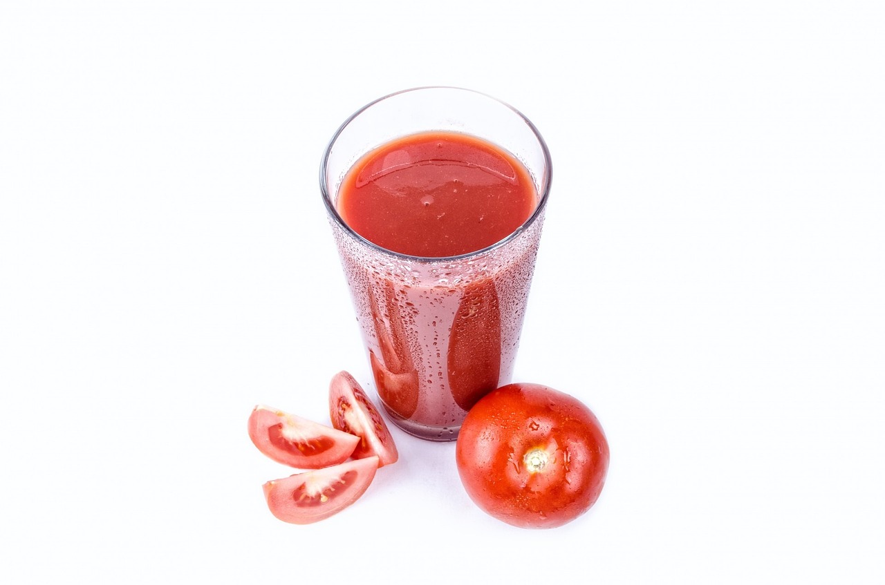 a glass of tomato juice next to a sliced tomato, productphoto, with a white background, listing image, zdzisław