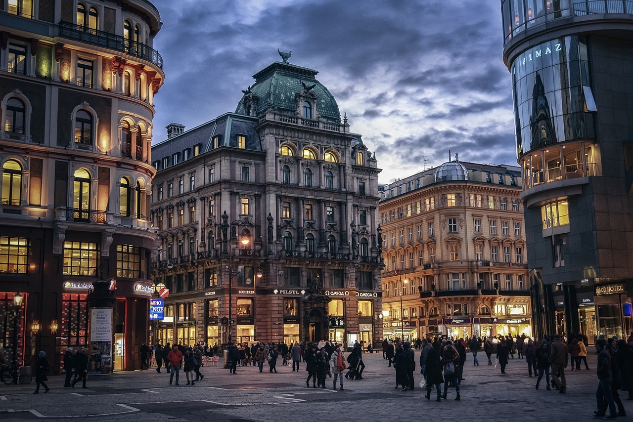 a group of people walking down a street next to tall buildings, pexels contest winner, viennese actionism, vienna state opera house, city street at dusk, hdr photo, austro - hungarian