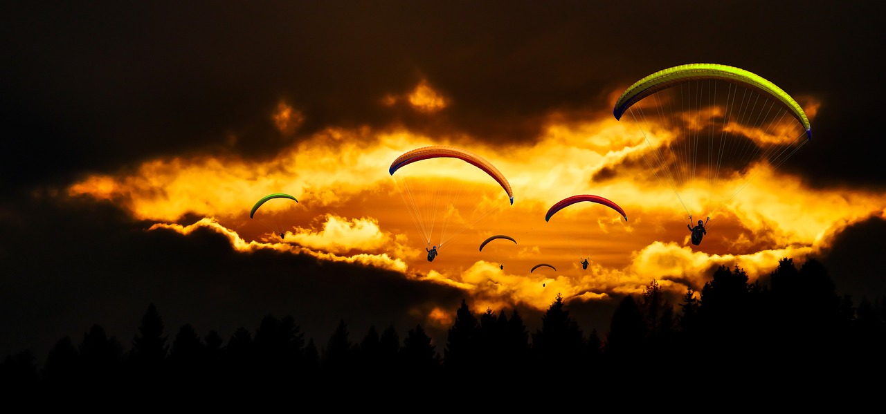 a group of paragliders flying through a cloudy sky, by Paweł Kluza, romanticism, dappled golden sunset, made with photoshop, vivid colors!, golden glow