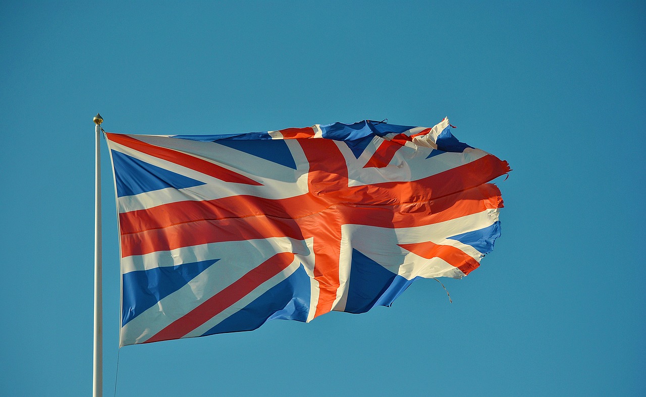 a british flag flying high in the sky, by David Simpson, photorealism. trending on flickr, blue and orange, piggy, unwind!