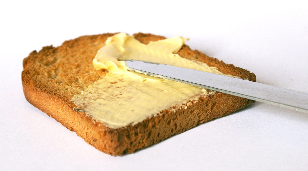 a piece of bread with butter and a knife, a picture, by John Rhind, cream, hyperdetalied, combine, mayo