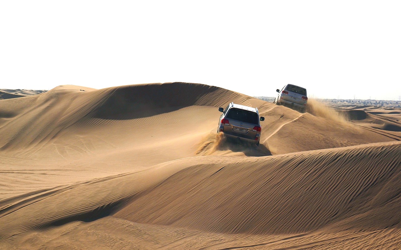 a couple of trucks that are in the sand, dau-al-set, car moving fast, majestic dunes, memorable scene, head-to-shoulder