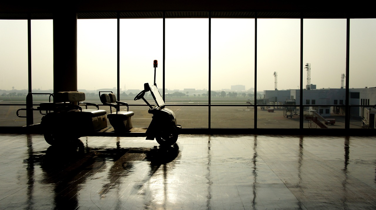 a scooter parked in front of a large window, a picture, by Yi Jaegwan, shutterstock, black. airports, desolate, cart, beijing