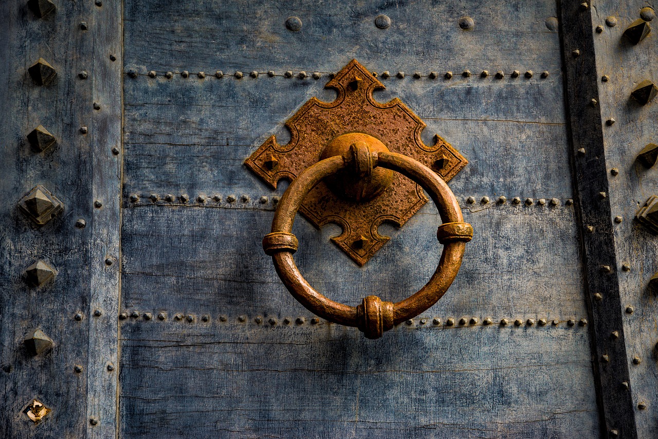 a close up of a metal door with a ring on it, a portrait, by Richard Carline, shutterstock contest winner, renaissance, earth tones and blues, medieval photograph, prize winning color photo, gold and indigo