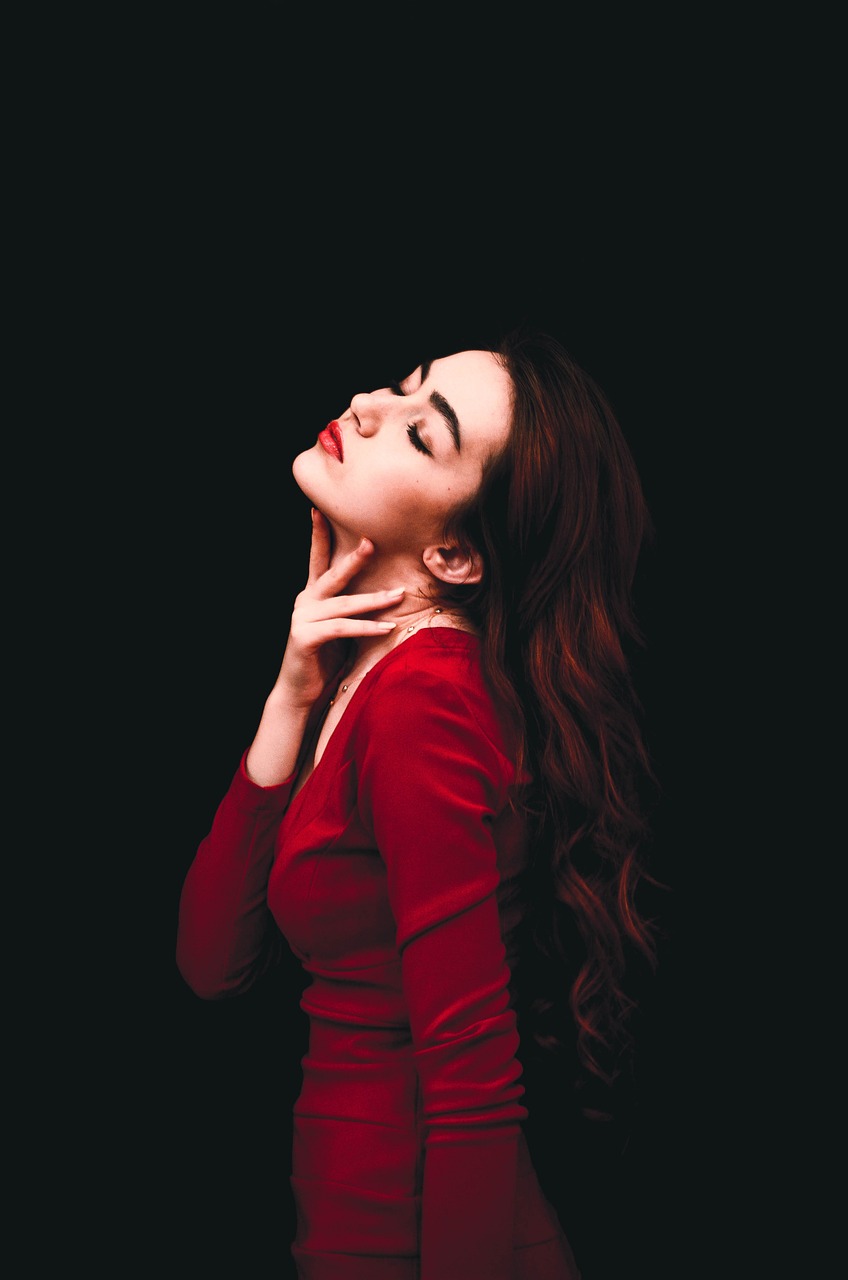 a woman in a red dress posing for a picture, a portrait, by Emma Andijewska, pexels, fashion model face closed eyes, on a black background, amouranth, a cute and beautiful young woman