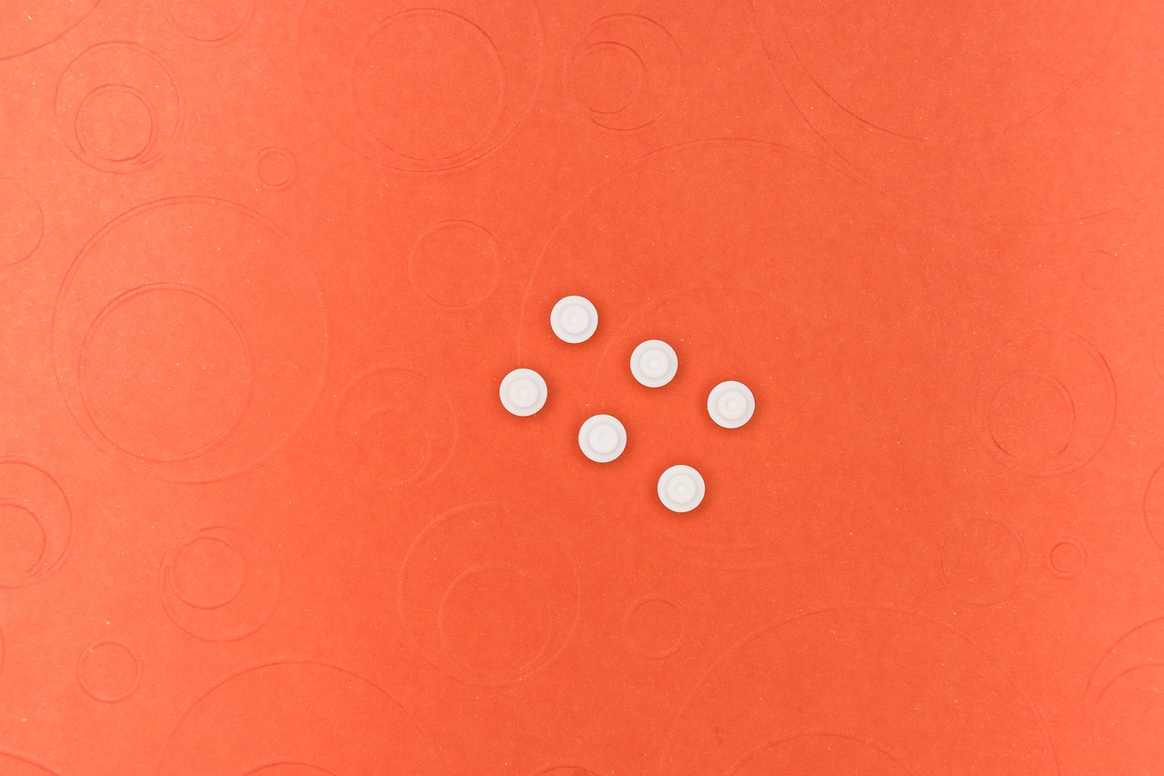 a group of white pills sitting on top of a red surface, a stock photo, by Jan Rustem, circles, miniature product photo, peach embellishment, on vellum