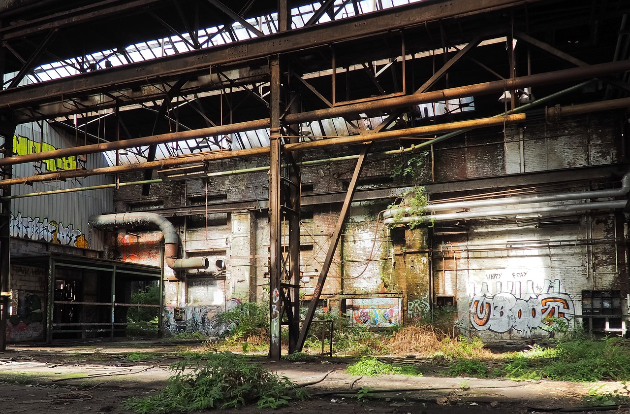 a building that has a bunch of graffiti on it, by Richard Carline, abandoned steelworks, hannover, jungle, postprocessed