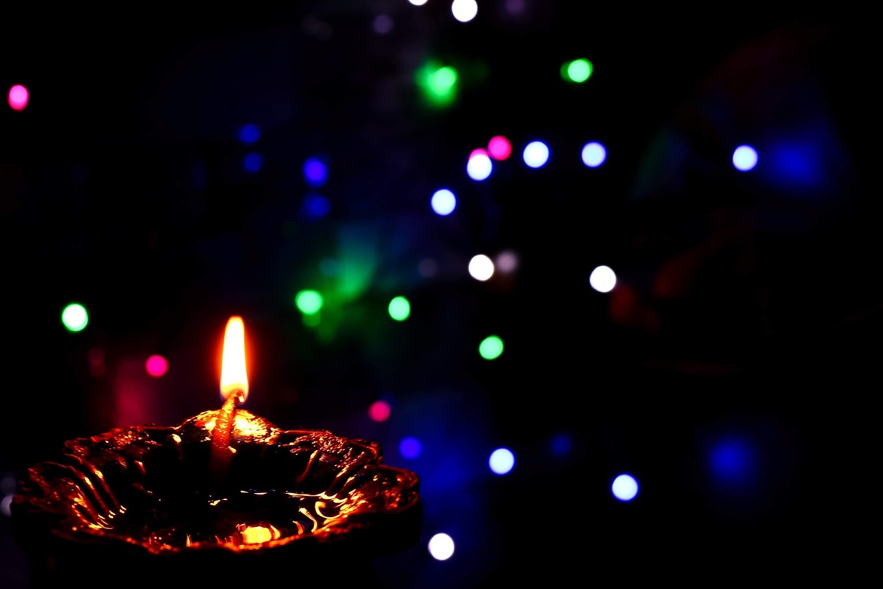 a lit candle in the dark with christmas lights in the background, by Max Dauthendey, pexels, light and space, floating lanterns, bokeh color background, video still, dof:-1